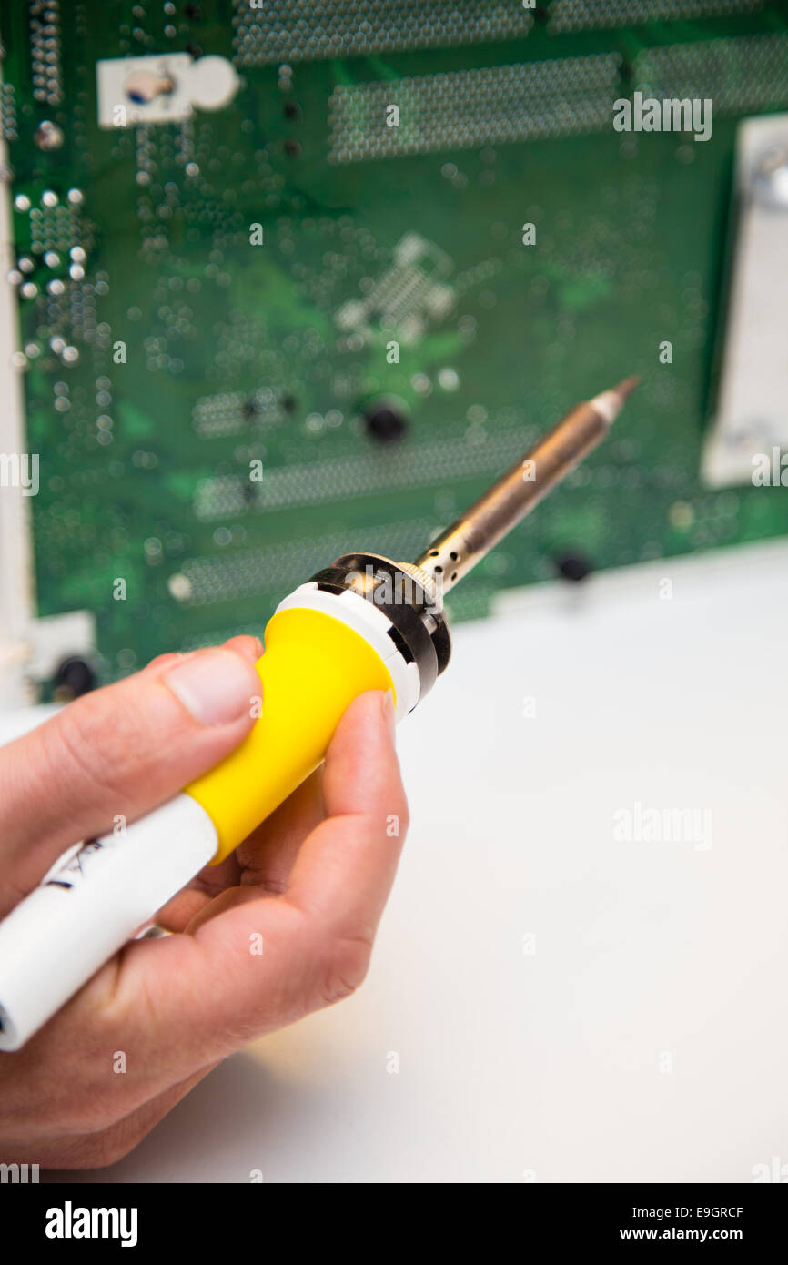 Les réparations de l'homme sur un circuit imprimé avec un fer à souder Banque D'Images