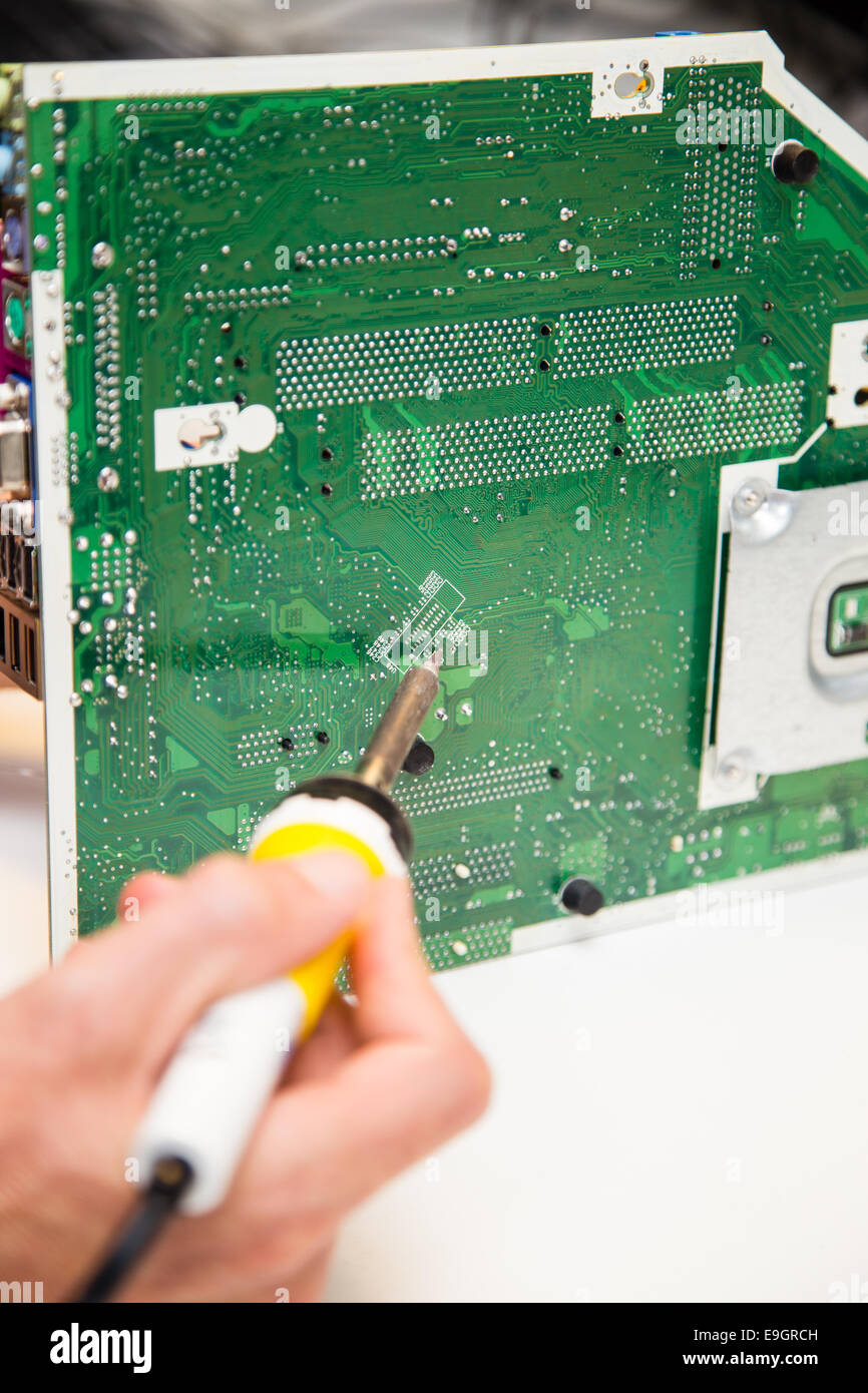 Les réparations de l'homme sur un circuit imprimé avec un fer à souder Banque D'Images