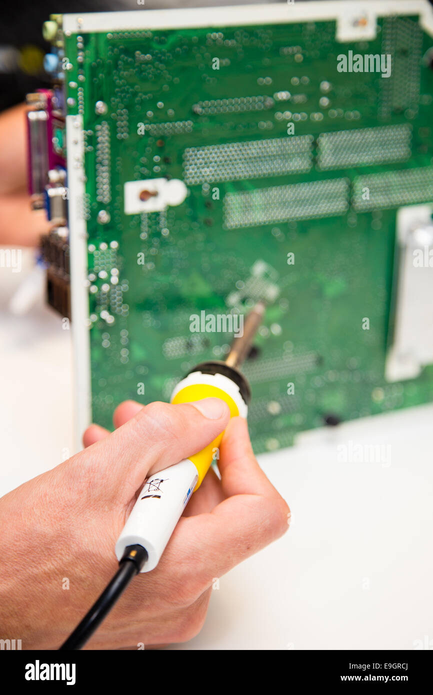 Les réparations de l'homme sur un circuit imprimé avec un fer à souder Banque D'Images