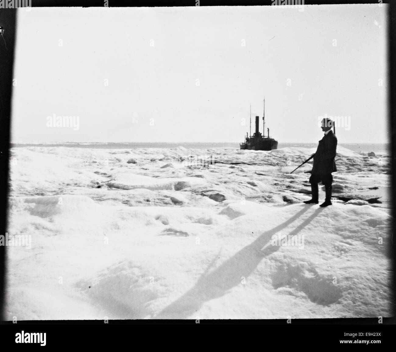 Cette image montre Jonas menti avec un fusil sur la glace solide de la mer de Kara dans l'Arctique, près de Karasjok, en Norvège. La photographie capture un moment lors d'une expédition de chasse, liée aux expéditions arctiques de Fridtjof Nansen. Banque D'Images