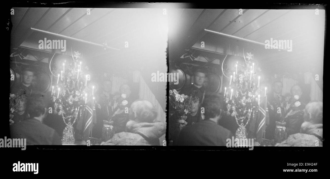 Cette photographie montre la célébration du réveillon de Noël (Julaften) dans le salon 'Maud' le 24 décembre 1918, lors de l'expédition Maud. L'image montre des membres de l'expédition, dont Roald Amundsen, marquant l'occasion festive lors de leur expédition polaire dans le passage du Nord-est. Banque D'Images