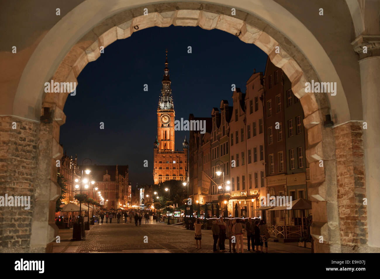 Vue à travers la porte verte ou vers les maisons Zielona Brama sur marché ou la rue Długi Targ et la tour de l'horloge de l'hôtel de ville Banque D'Images