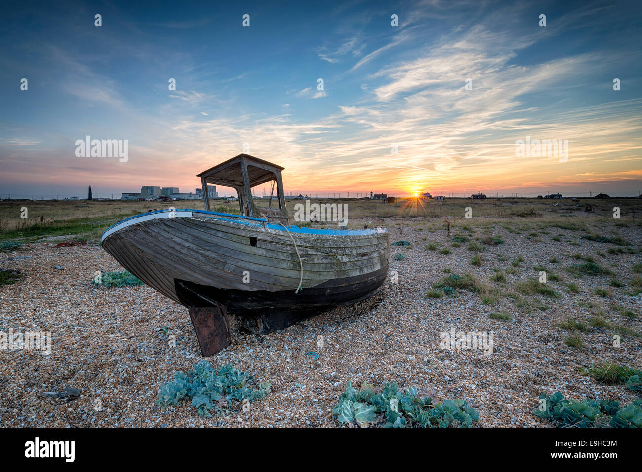 Coucher de soleil sur un vieux bateau en bois échoué sur une plage de galets Banque D'Images
