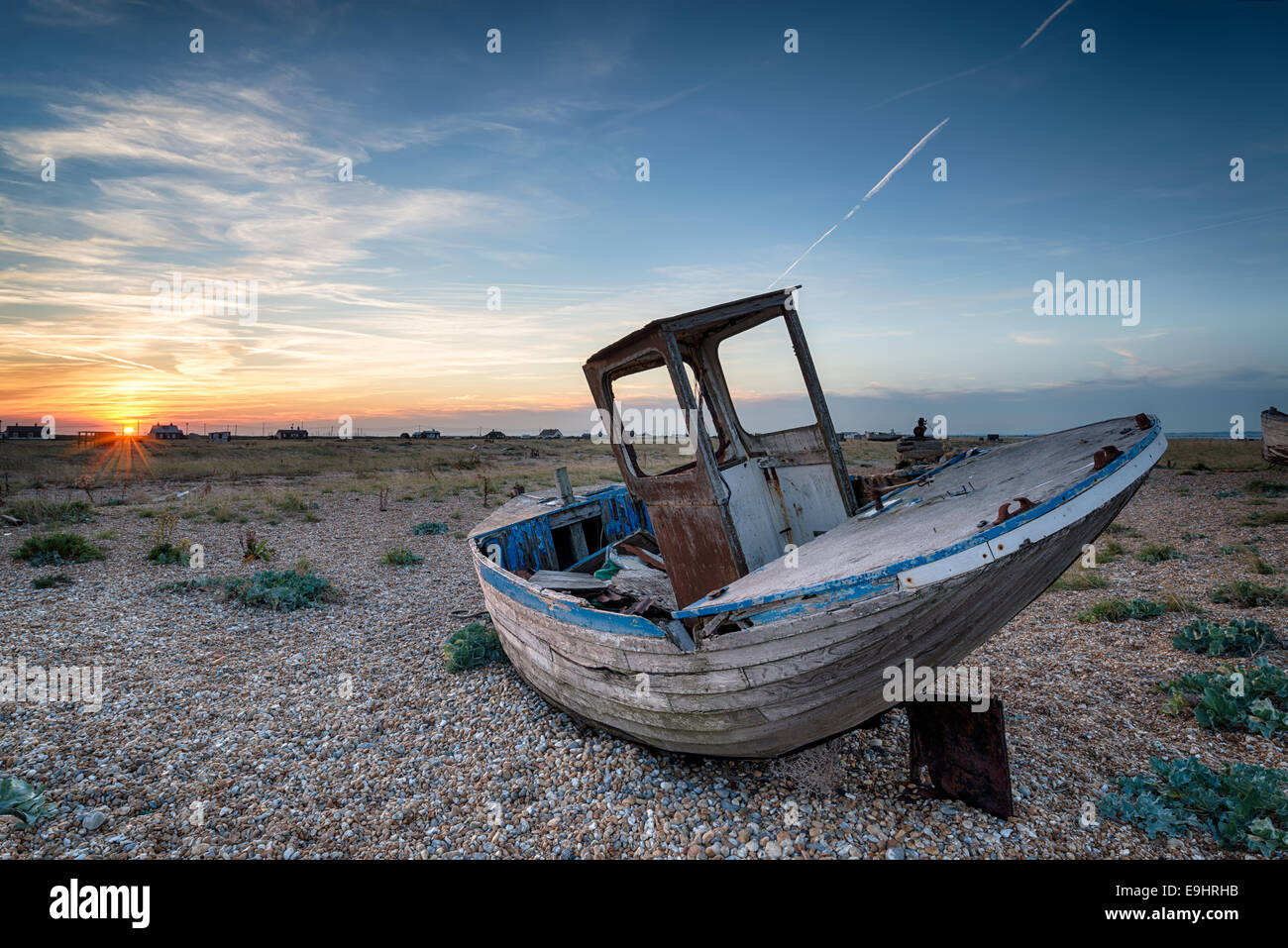 Un vieux bateau de pêche en bois abandonnés avec des filets échoués sur une plage de galets Banque D'Images