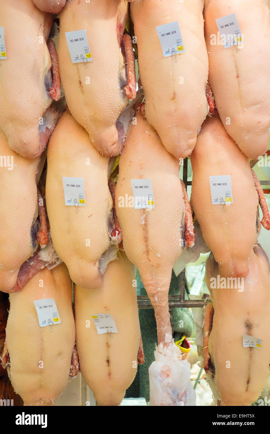 Les oies plumées pendre hors une boucherie à Oxford's marché couvert prêt pour Noël Banque D'Images