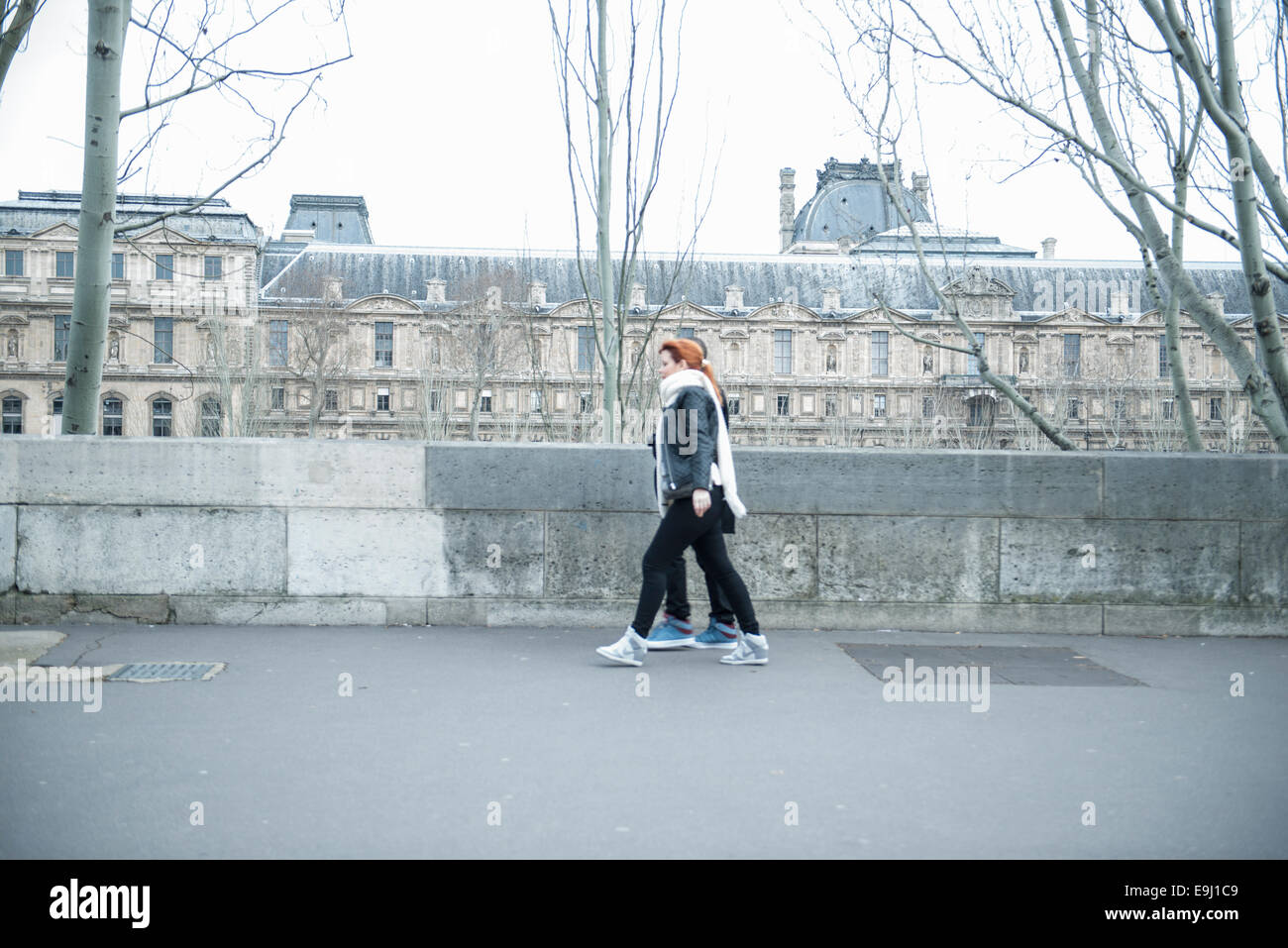 Un jeune couple se promener le long d'une rue à paris habillé chaud dans les écharpes sur un jour gris Banque D'Images