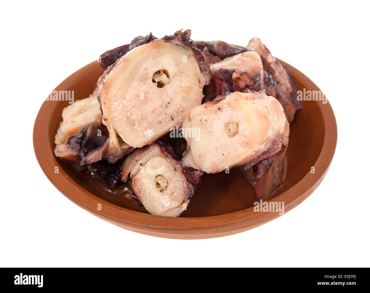 Une petite assiette de poulpe cuit avec une sauce à l'ail dans un petit bol sur un fond blanc. Banque D'Images
