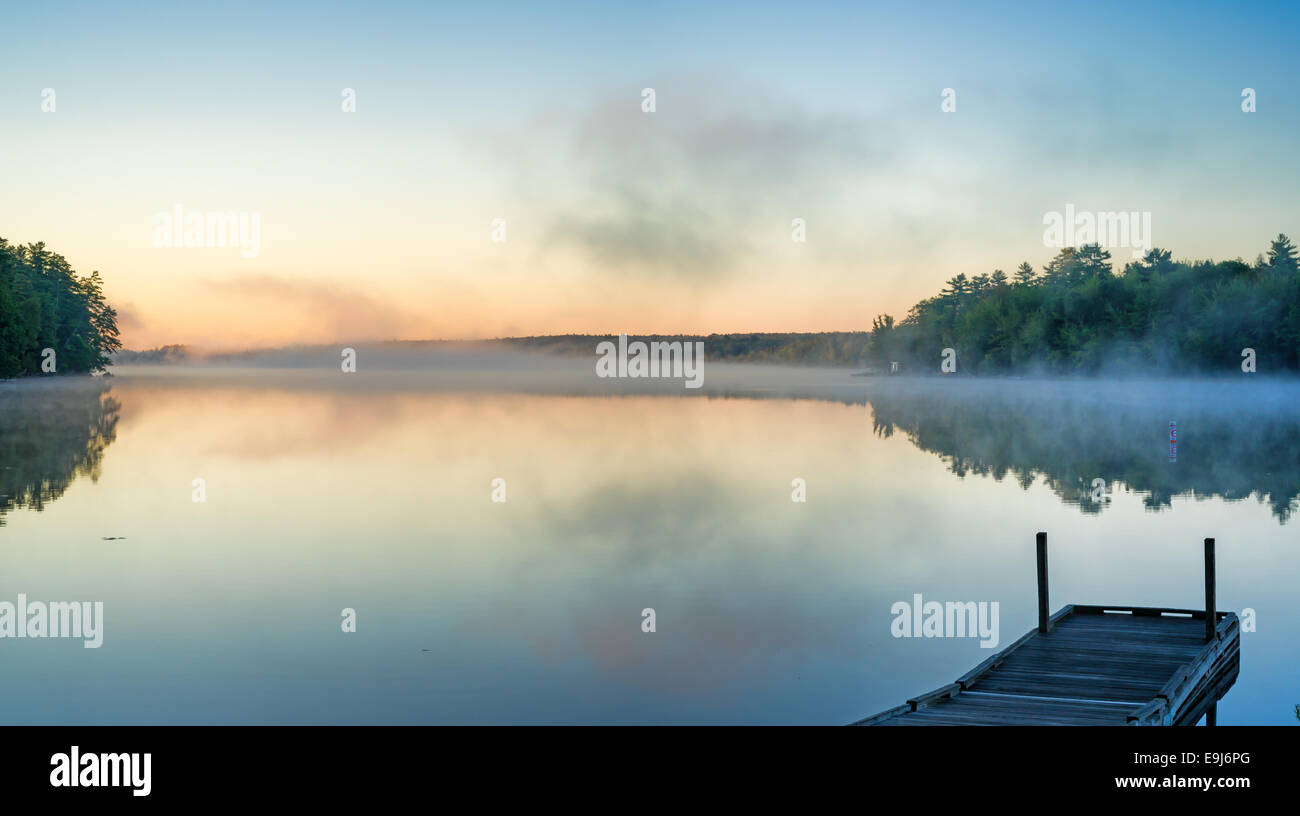Étang Toddy, Maine, tôt le matin avec la lumière reflétée de la brume au-dessus de l'eau et un petit bateau quai dans l'avant-plan. Banque D'Images