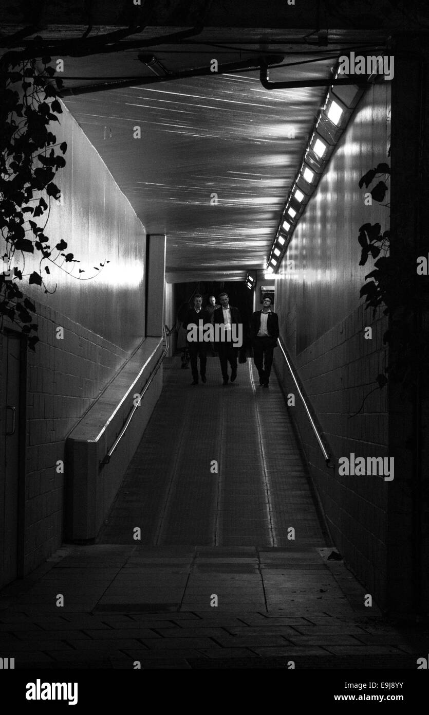 Groupe d'hommes marcher dans un endroit sombre, mais éclairé de nuit passage souterrain. Banque D'Images