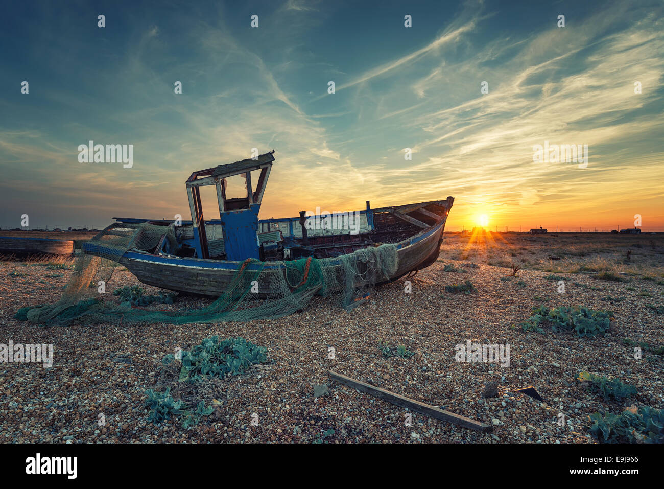 Effet Vintage bateau de pêche au lever du soleil sur une plage de galets Banque D'Images