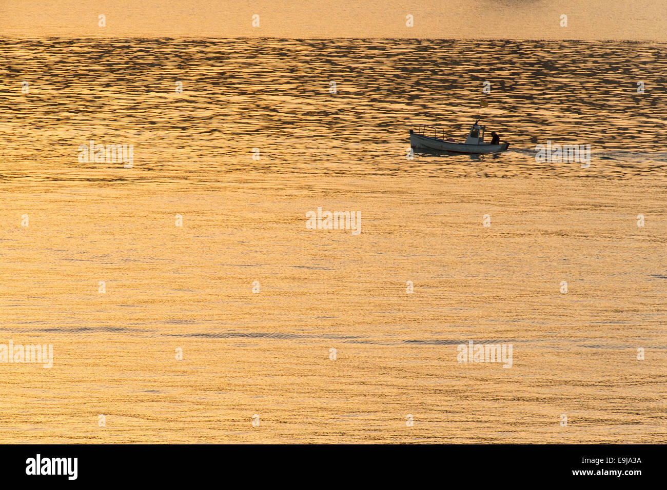 Un petit bateau de pêche en mer au coucher de soleil. Banque D'Images