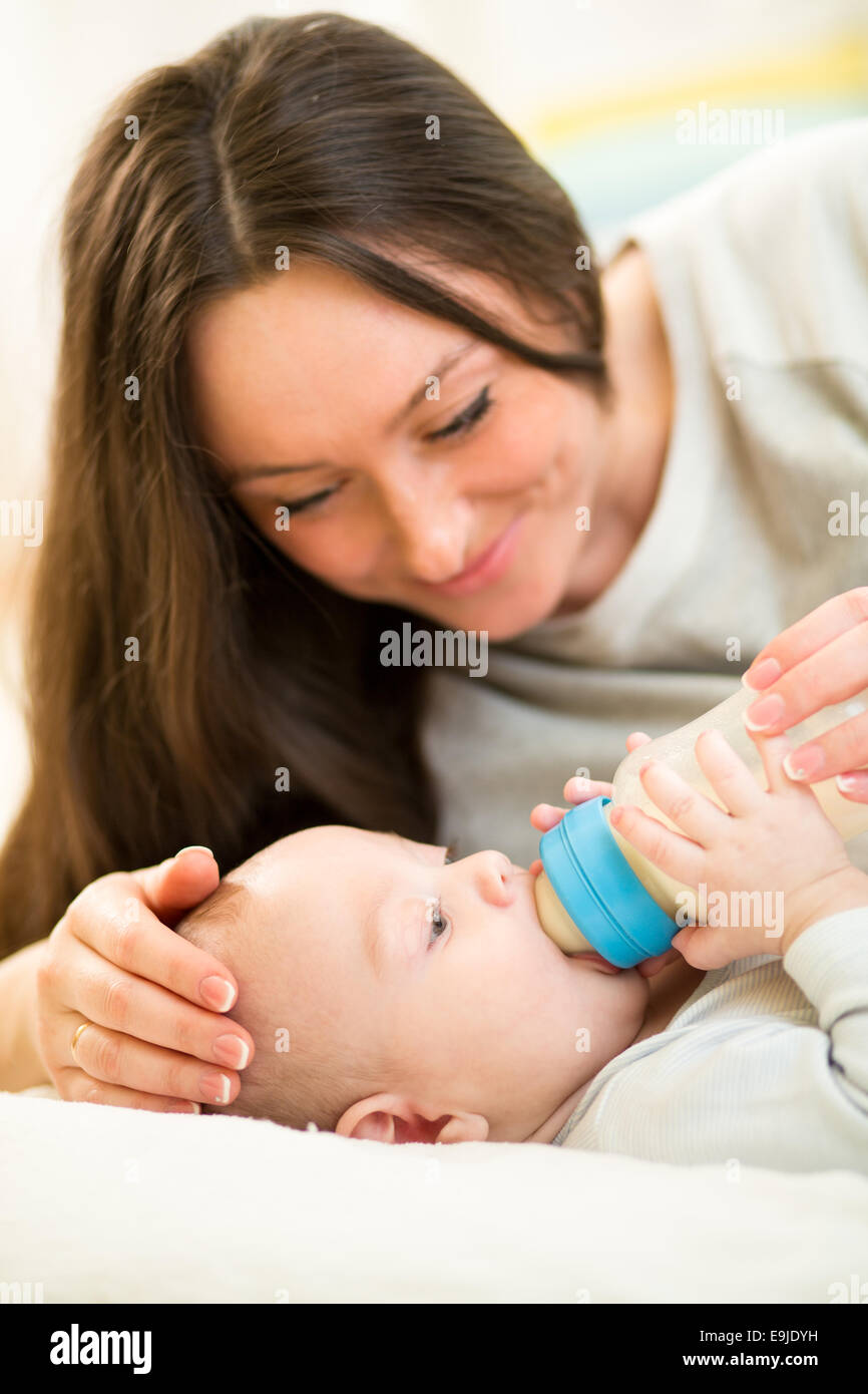 La mère à la maison nourrir bébé garçon avec une bouteille de lait Banque D'Images
