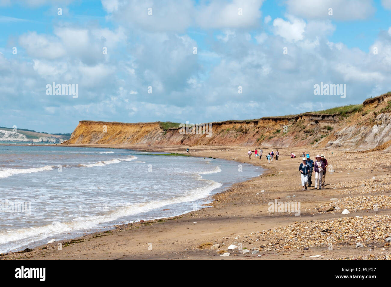 Les vacanciers en marchant le long de la plage au Brook Bay sur la côte sud de l'île de Wight. Banque D'Images