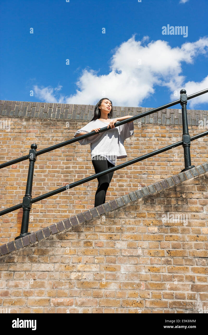 Low angle view of woman leaning on railing tout contre ciel nuageux Banque D'Images