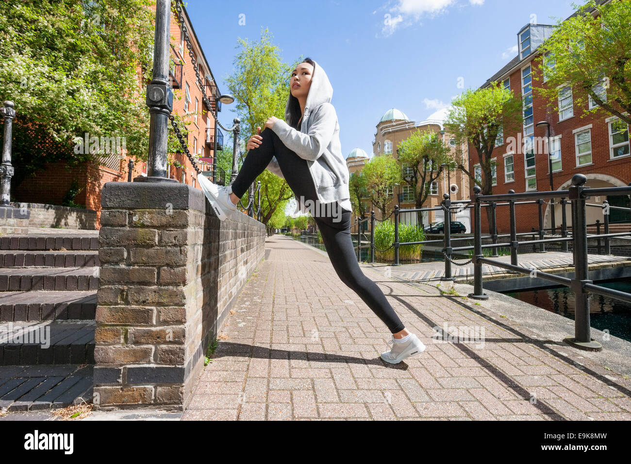 Vue latérale sur toute la longueur des jeunes fit woman stretching on sidewalk Banque D'Images