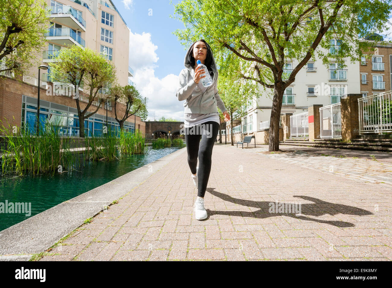 Toute la longueur de fit young woman jogging par canal contre les bâtiments Banque D'Images