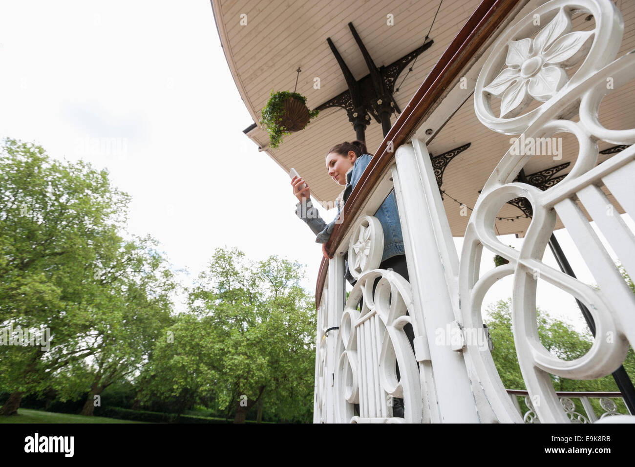 Low angle view of young woman using cell phone on porch Banque D'Images