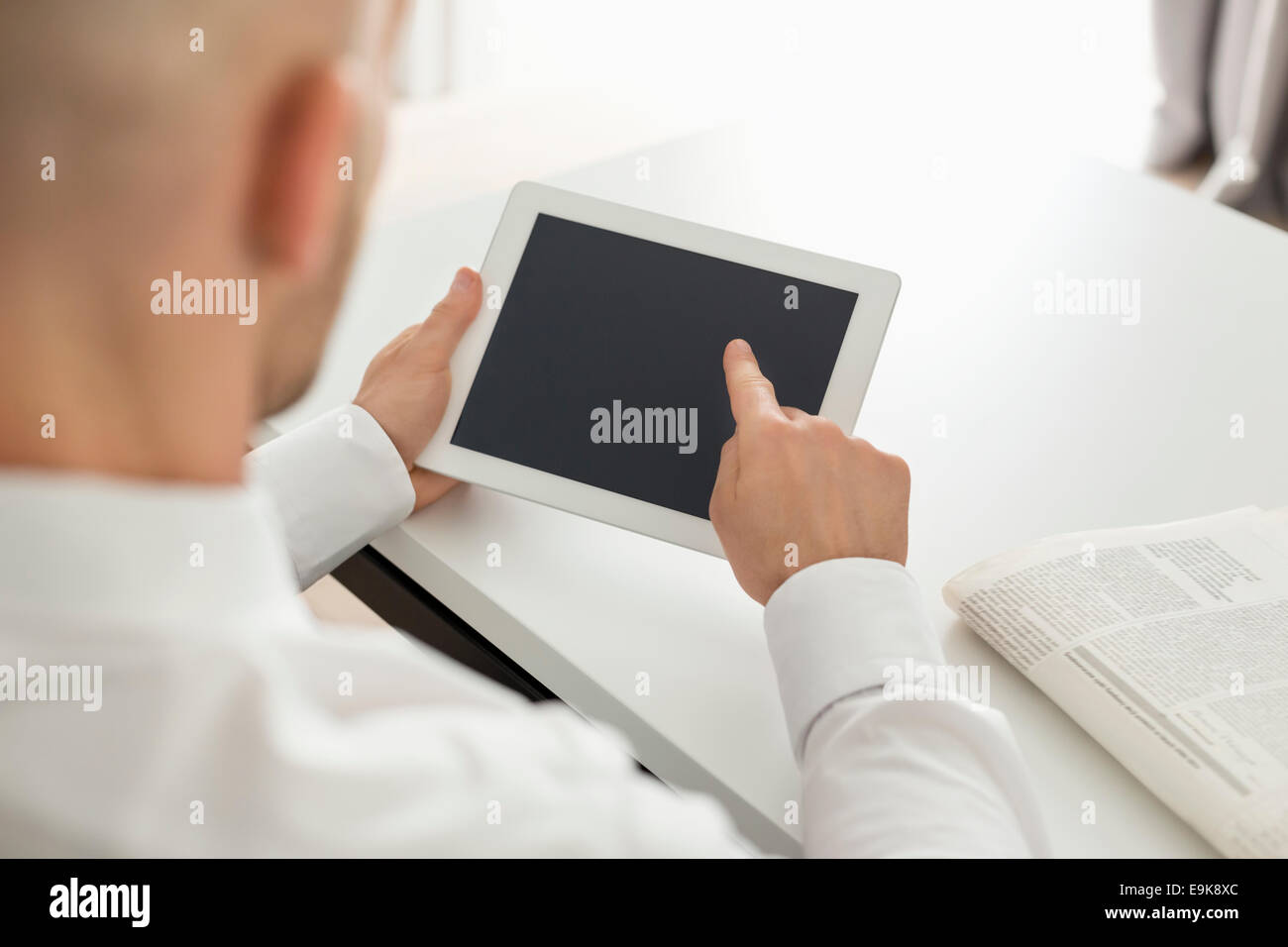 Mid adult businessman using digital computer at table in home office Banque D'Images