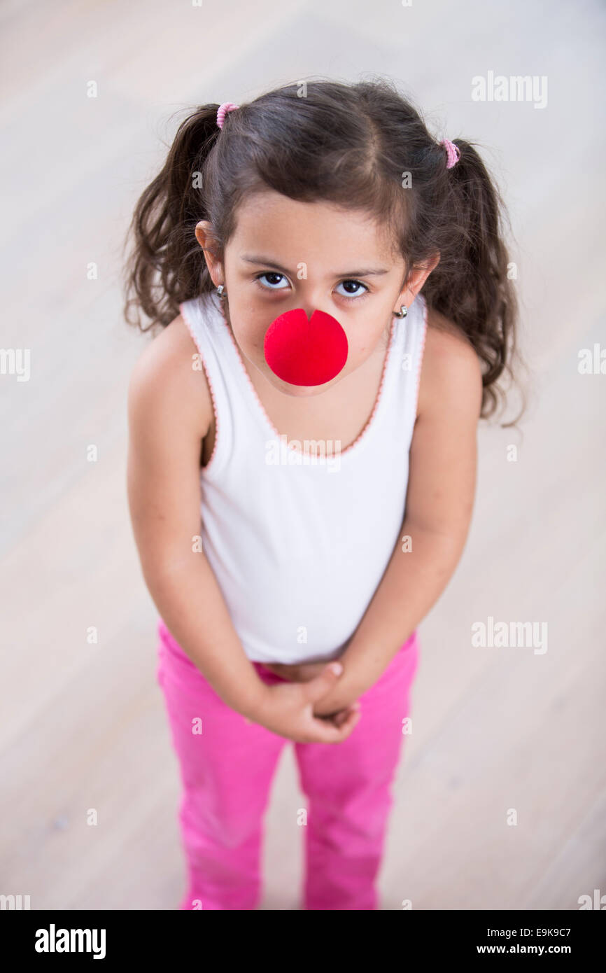 Portrait of cute little girl wearing clown nose à la maison Banque D'Images