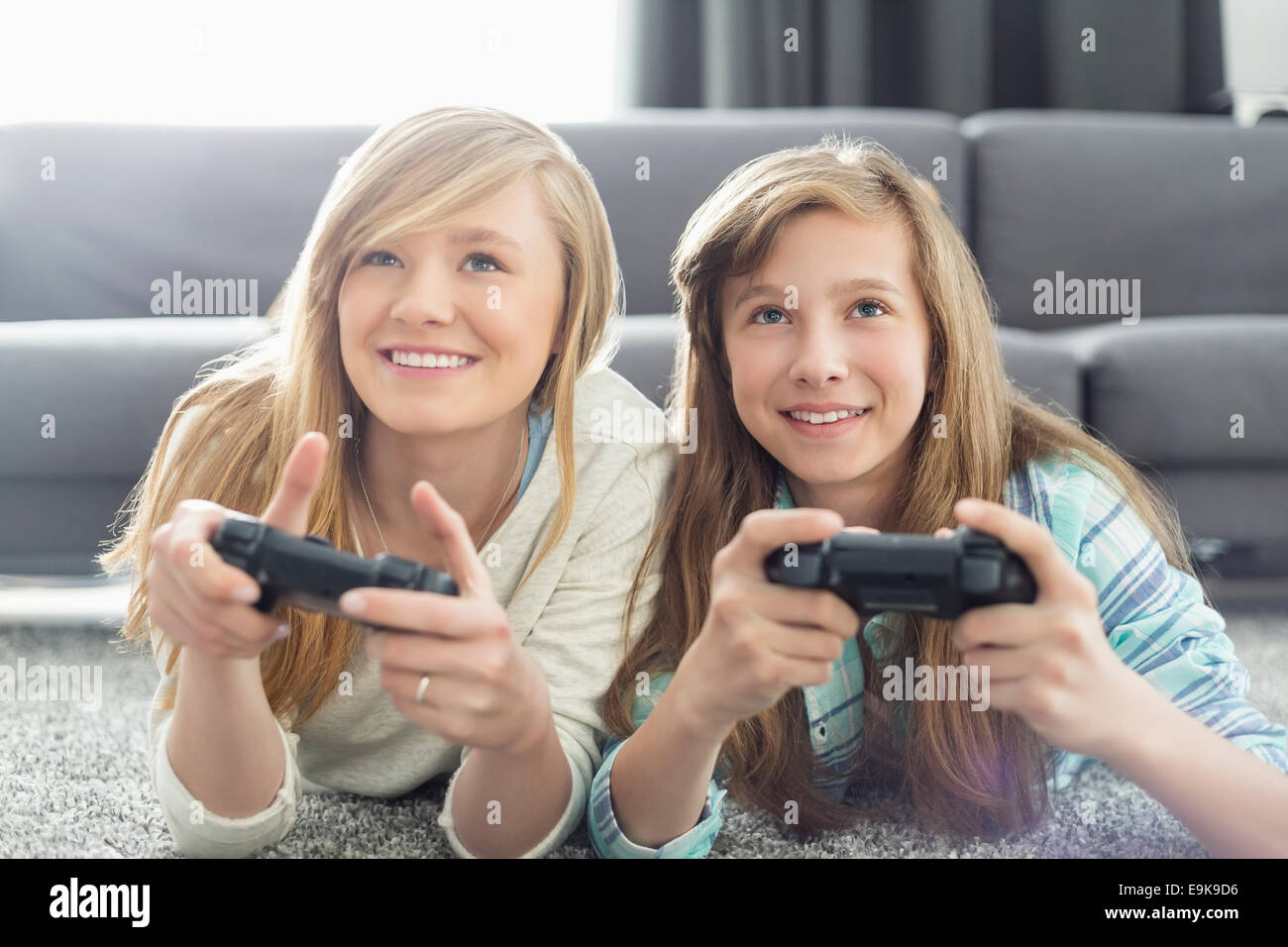 Soeurs à jouer à des jeux vidéo dans la salle de séjour Banque D'Images