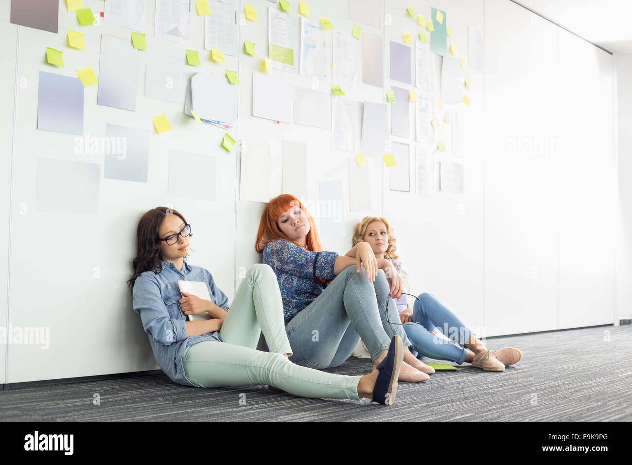 Fatigué businesswomen sitting on floor in creative office Banque D'Images
