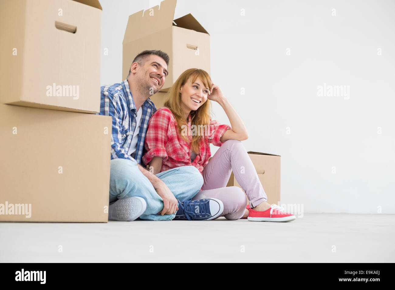 Full-length of happy couple sitting in new house Banque D'Images