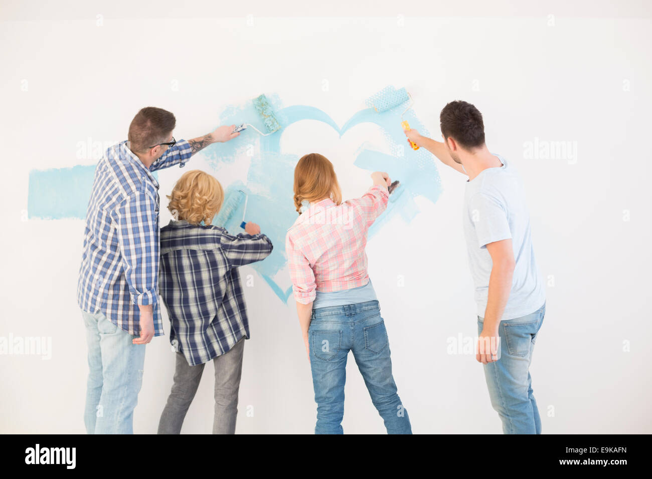 Vue arrière de couples painting wall in new home Banque D'Images