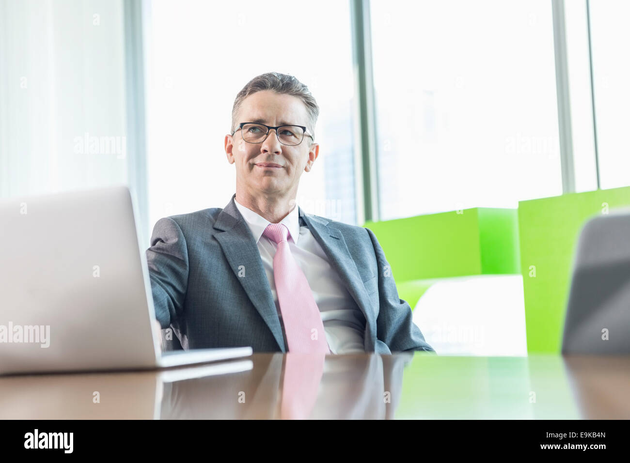 Middle-aged man with laptop sitting at conference table Banque D'Images