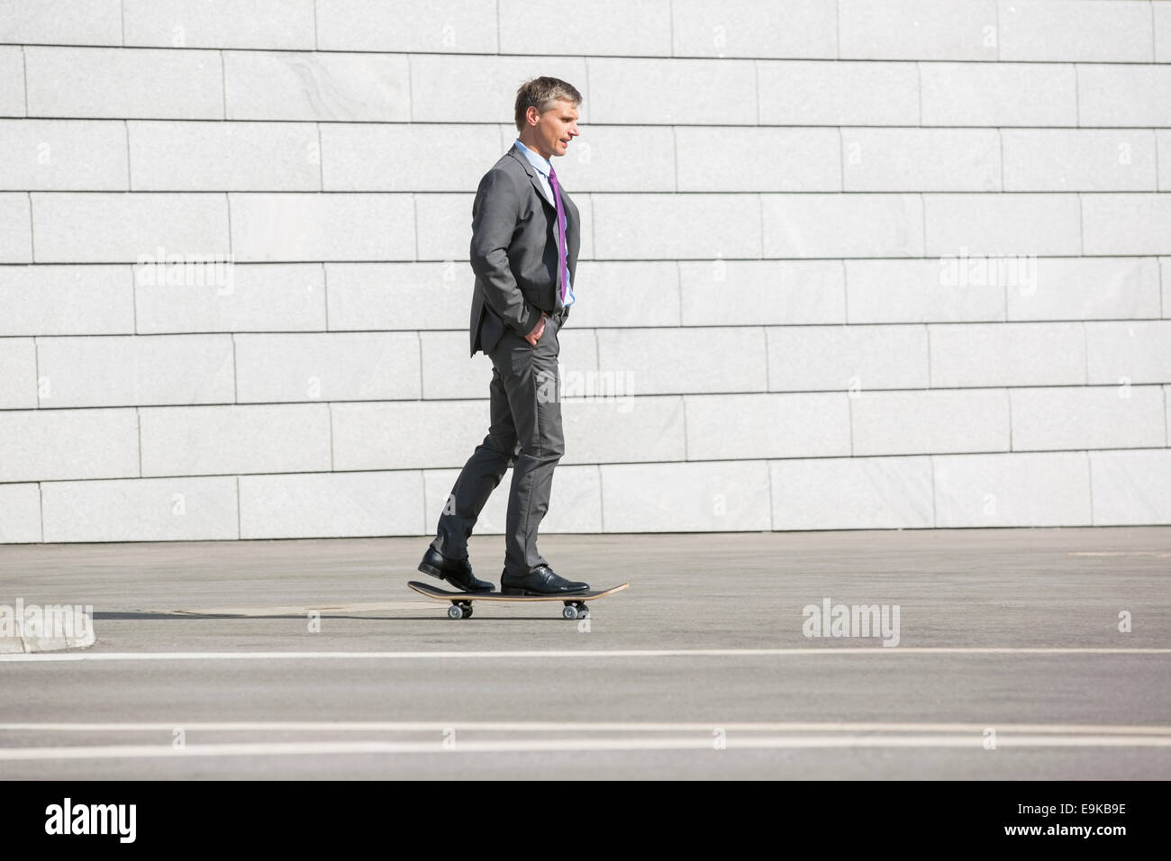 Businessman skateboarding on street Banque D'Images