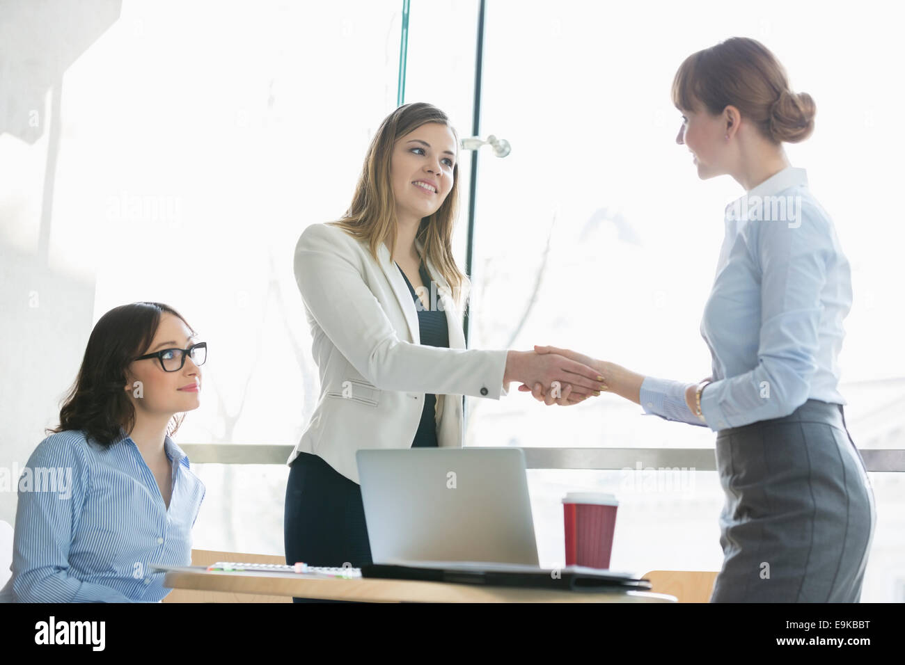 High angle view of businesswomen shaking hands at table in office Banque D'Images