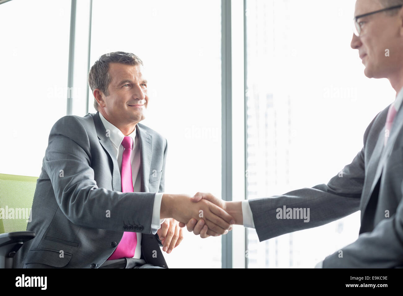 Mature businessmen shaking hands in office Banque D'Images