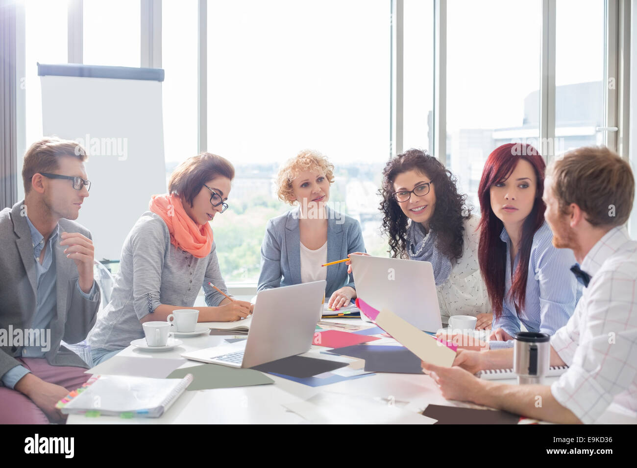 Des collègues de discuter plus de photos at conference table in creative office Banque D'Images