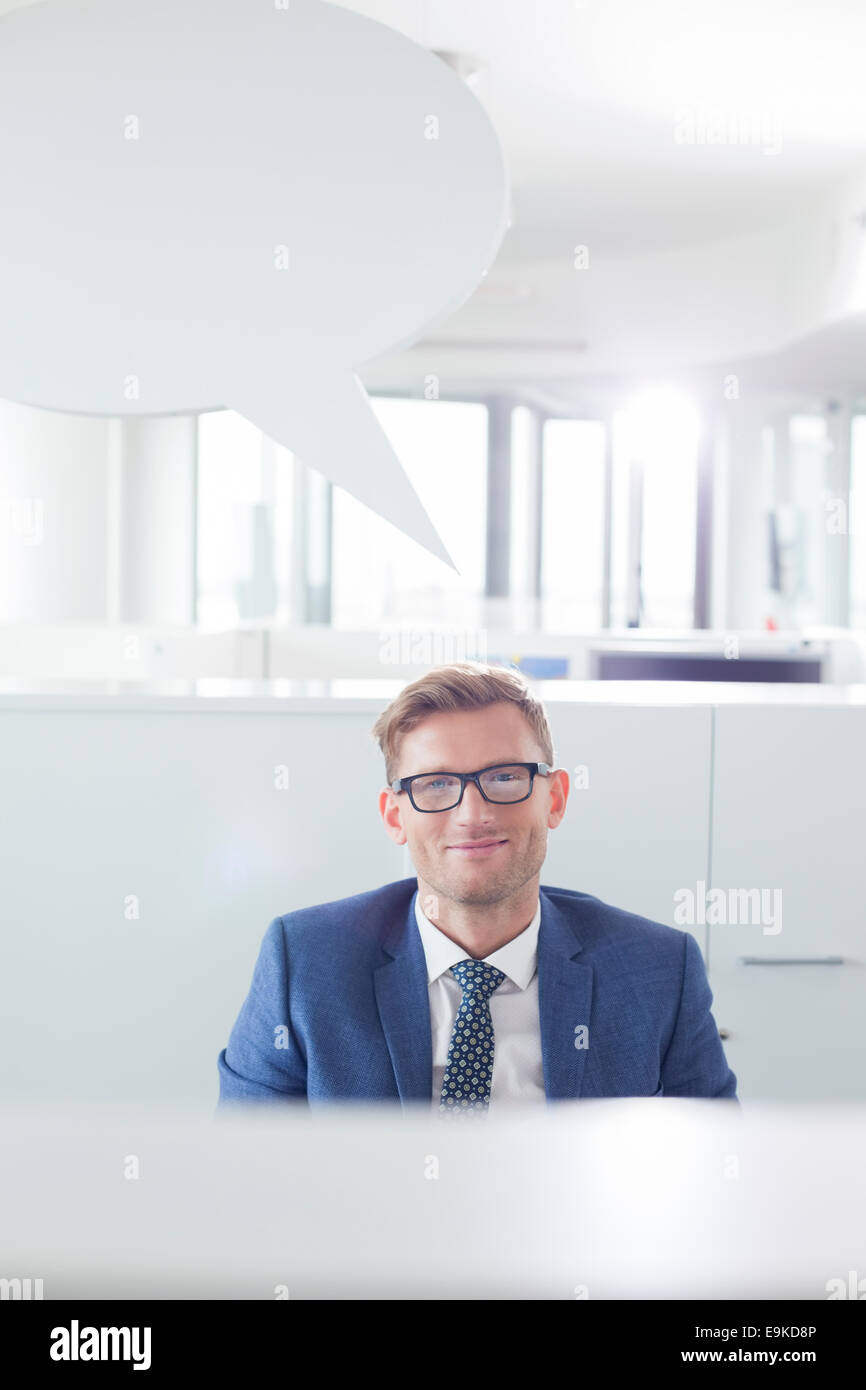 Portrait of smiling businessman with speech bubble in office Banque D'Images
