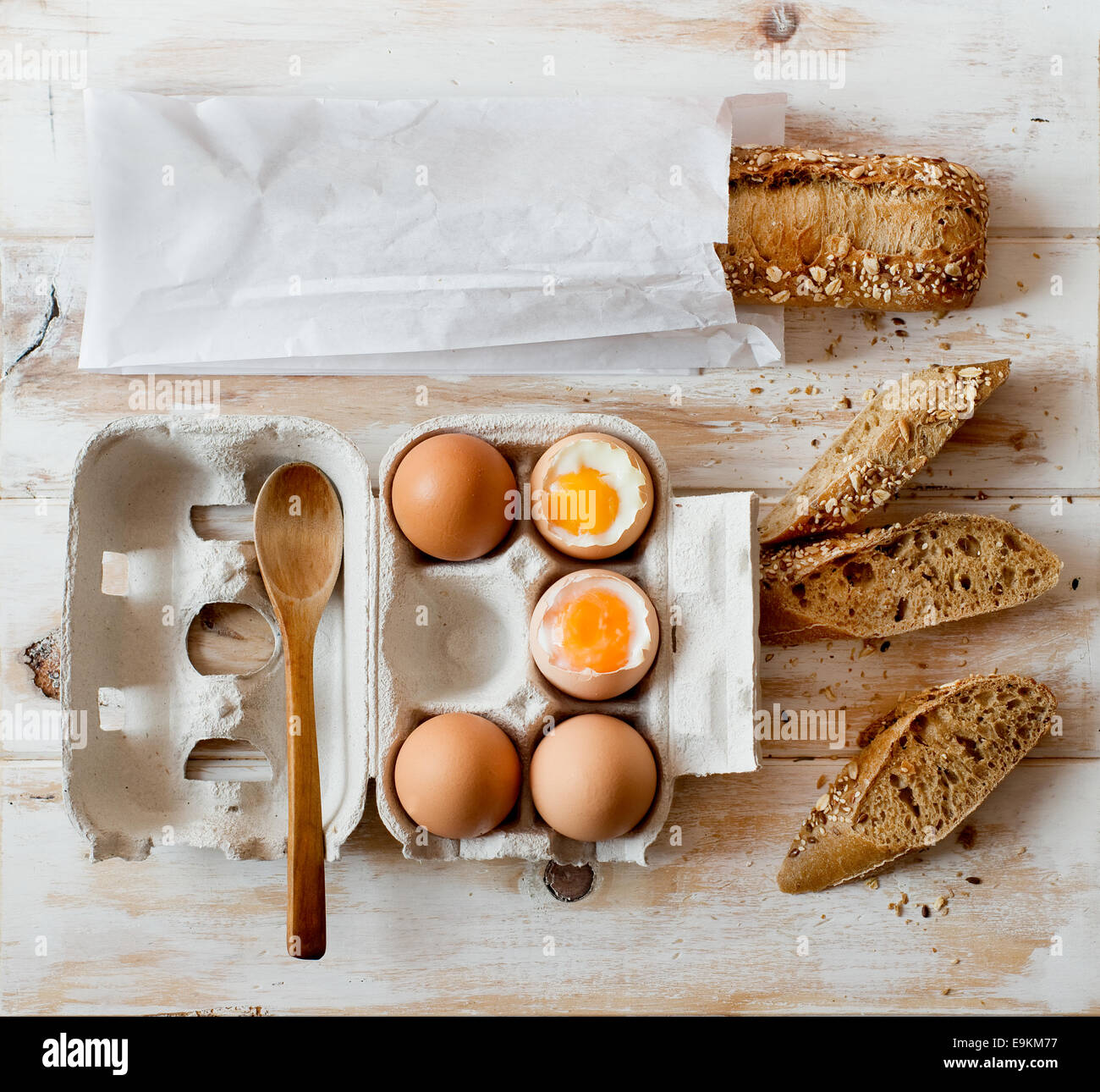 Oeufs à la coque dans une caisse de carton et du pain complet sur une table rustique. Banque D'Images