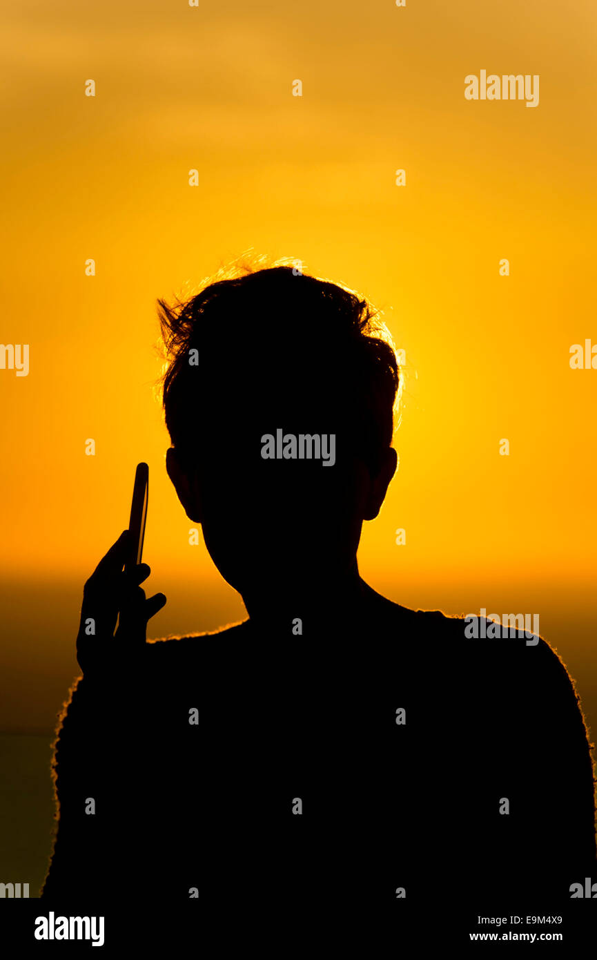 Une femme utilise un téléphone mobile sur un réseau d'itinérance à l'étranger pendant les vacances durant le coucher du soleil lever du soleil. Banque D'Images
