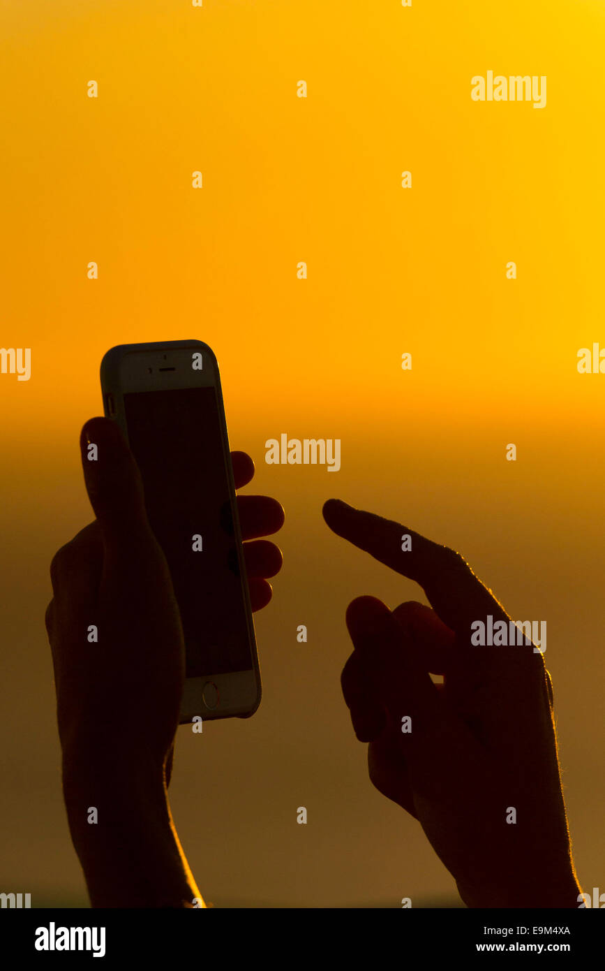 Une femme utilise un téléphone mobile sur un réseau d'itinérance à l'étranger pendant les vacances durant le coucher du soleil lever du soleil. Banque D'Images