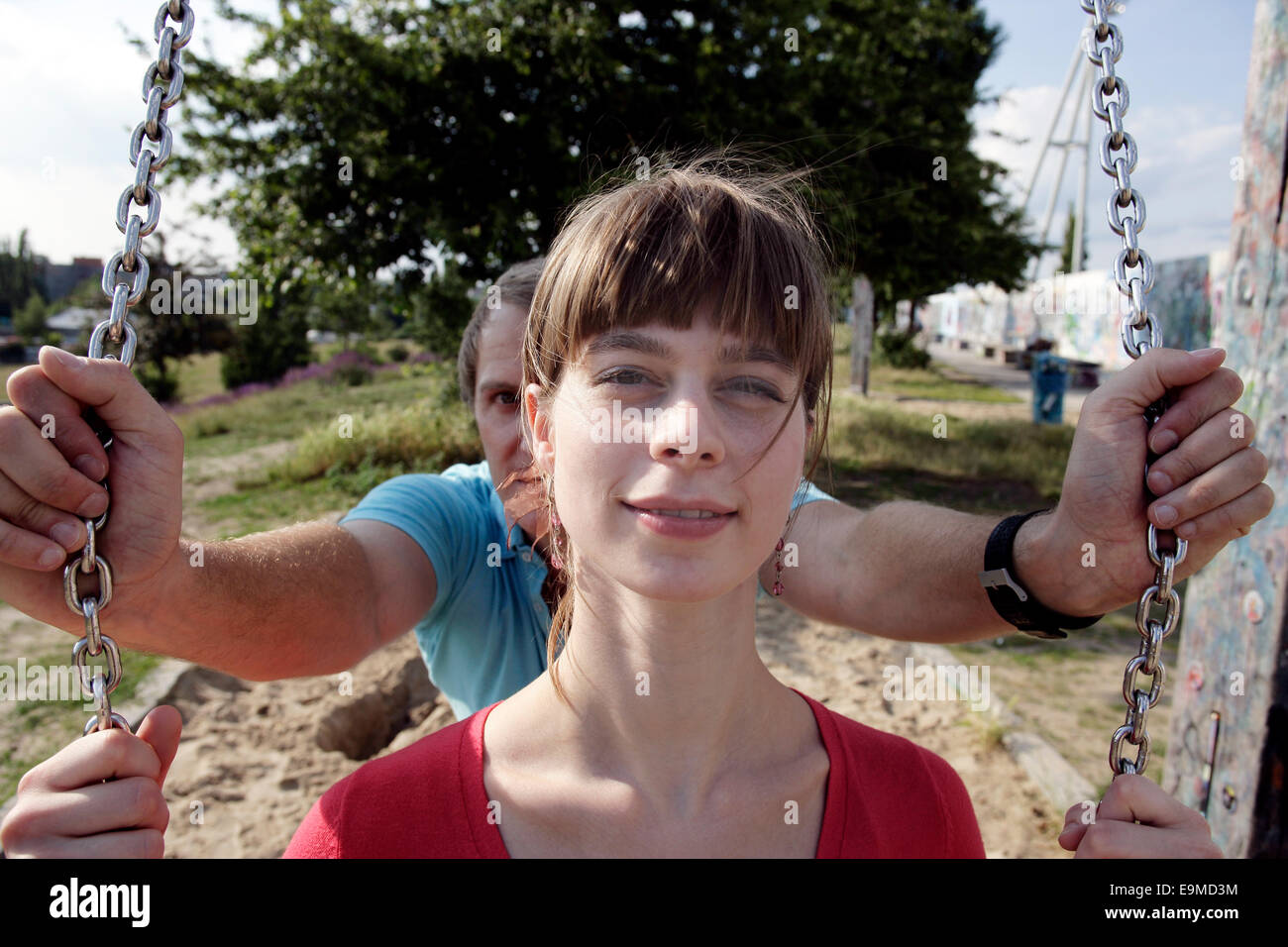 Man pushing woman on swing aire Banque D'Images