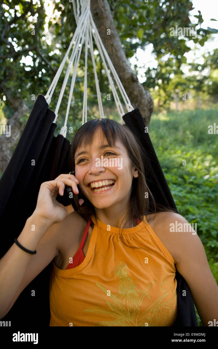 Jeune femme assise dans le hamac et talking on mobile phone Banque D'Images