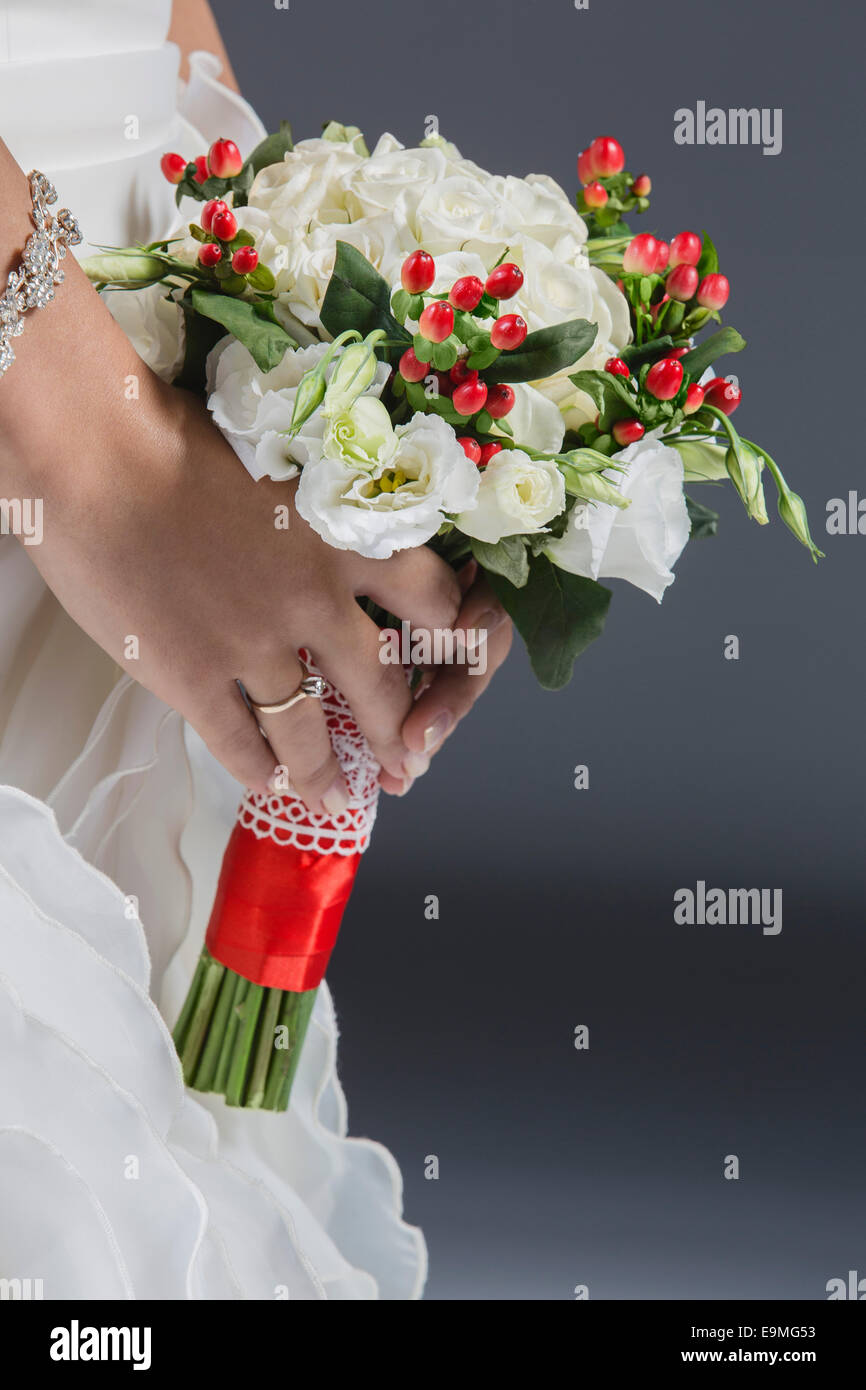 Portrait bride holding bouquet contre l'arrière-plan gris Banque D'Images