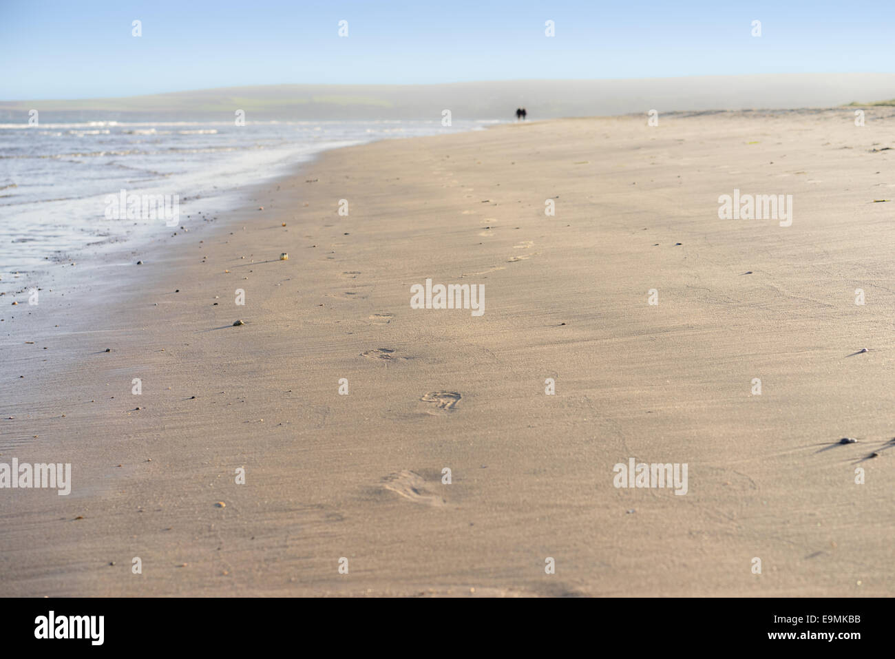 Plage de sable à Studland près de Sandbanks dans Dorset avec des empreintes de pas dans le sable et un couple disparaissant au loin Banque D'Images