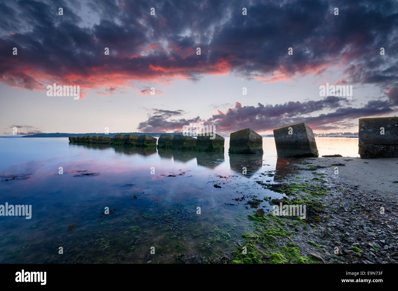 Un lever de soleil sur les cubes de béton, ancien WWII tank défense Studland beach dans le Dorset Banque D'Images