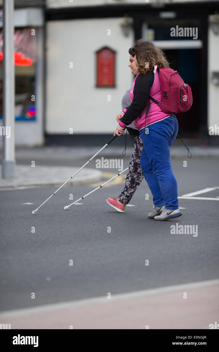Deux malvoyants déficients visuels des femmes par une route, à l'aide de bâtons blancs, UK Banque D'Images
