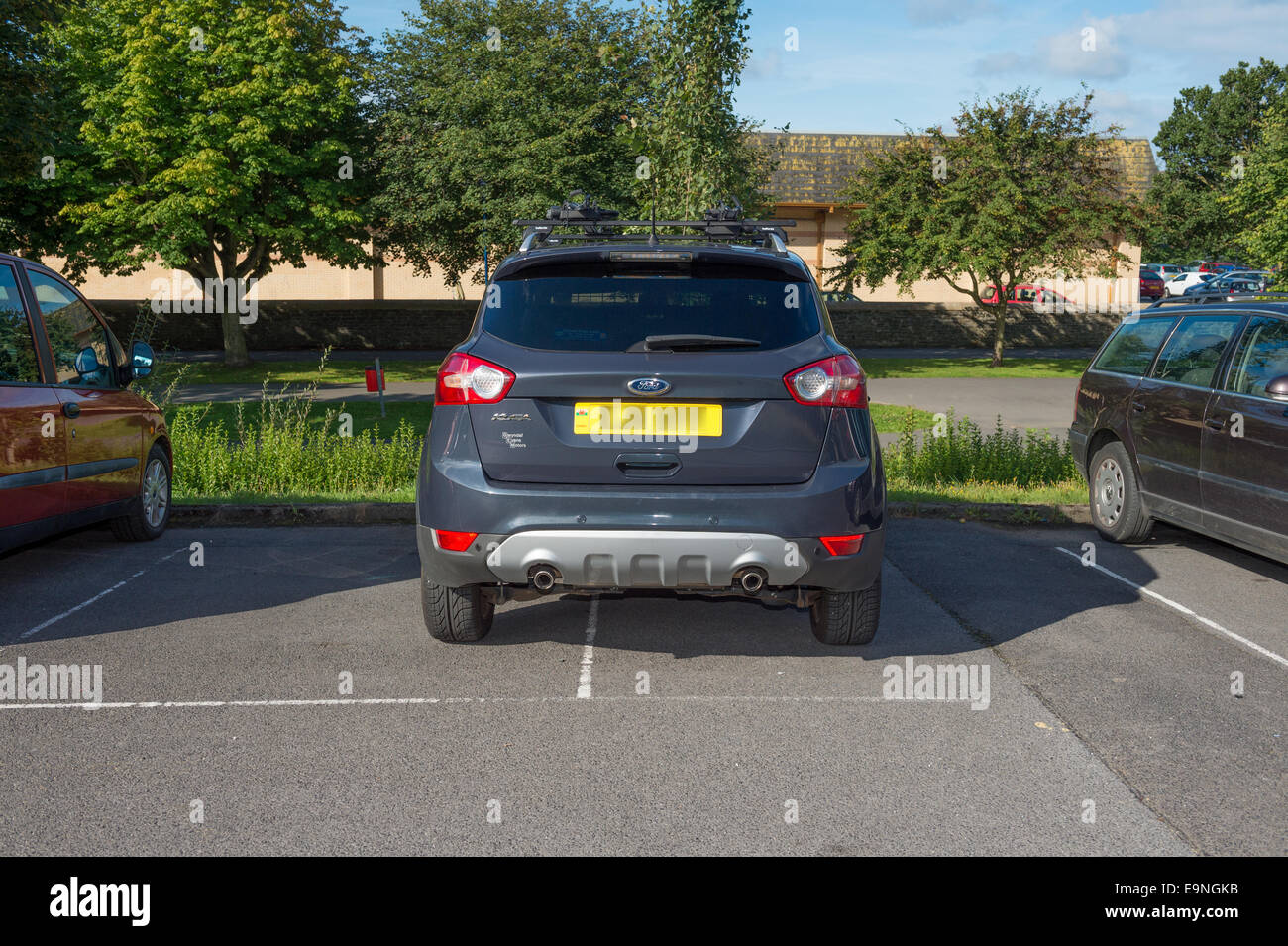 Mauvais Parking : Un 4x4 mal garé à cheval sur deux places de stationnement dans un parking UK (floue) de plaque Banque D'Images