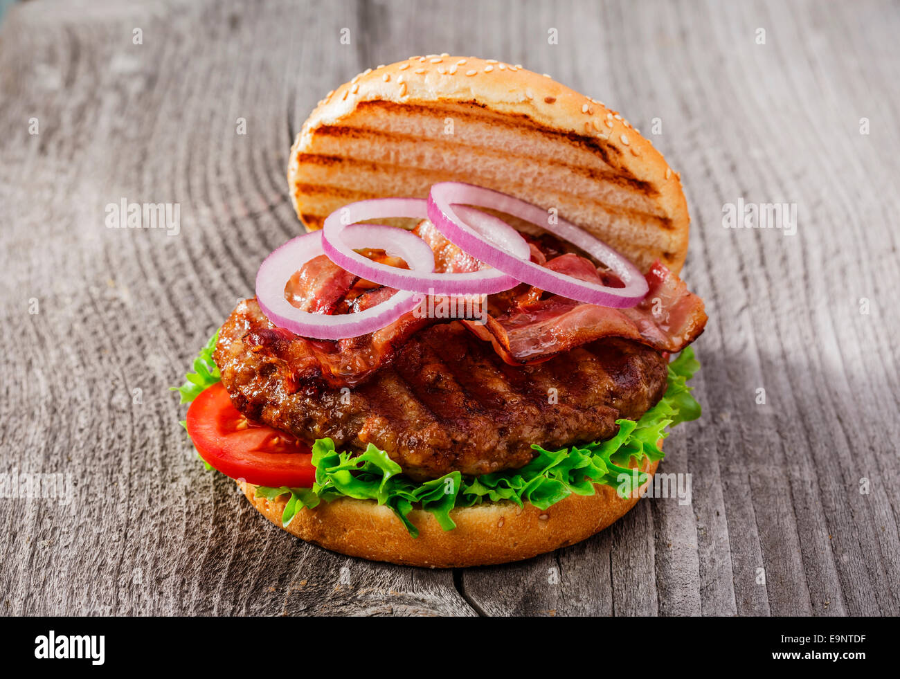 Hamburger avec bacon et la viande grillée sur une surface en bois Banque D'Images