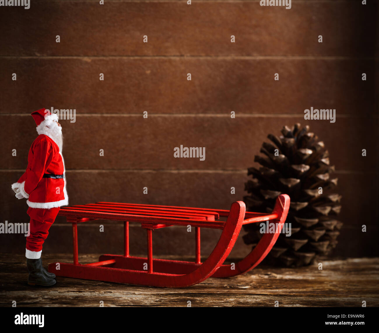 Traîneau en bois brun rouge avec cône de pin et le Père Noël Banque D'Images