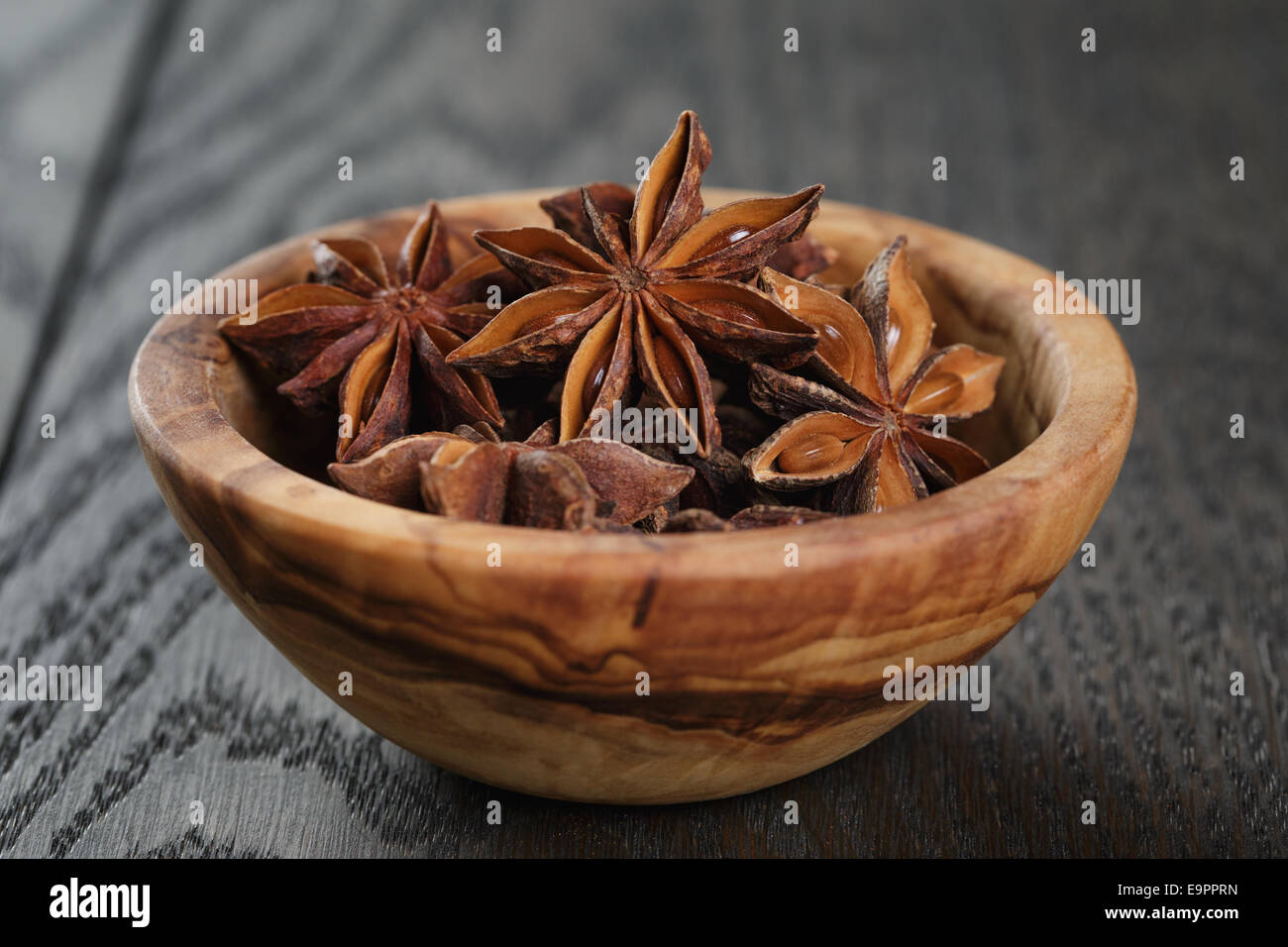 Étoiles d'anis dans un bol d'olive sur table en chêne, style rustique Banque D'Images