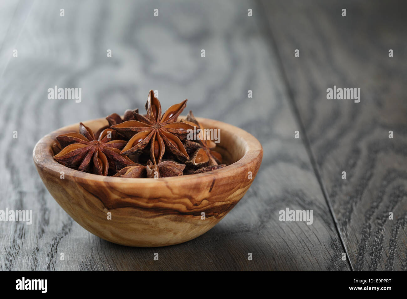 Étoiles d'anis dans un bol d'olive sur table en chêne, style rustique Banque D'Images