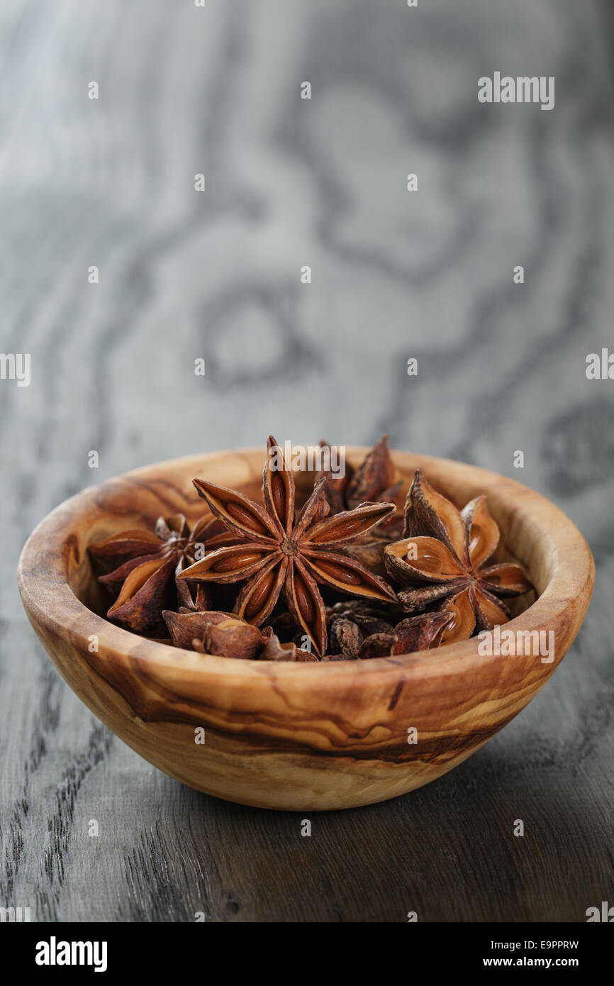 Étoiles d'anis dans un bol d'olive sur table en chêne, style rustique Banque D'Images