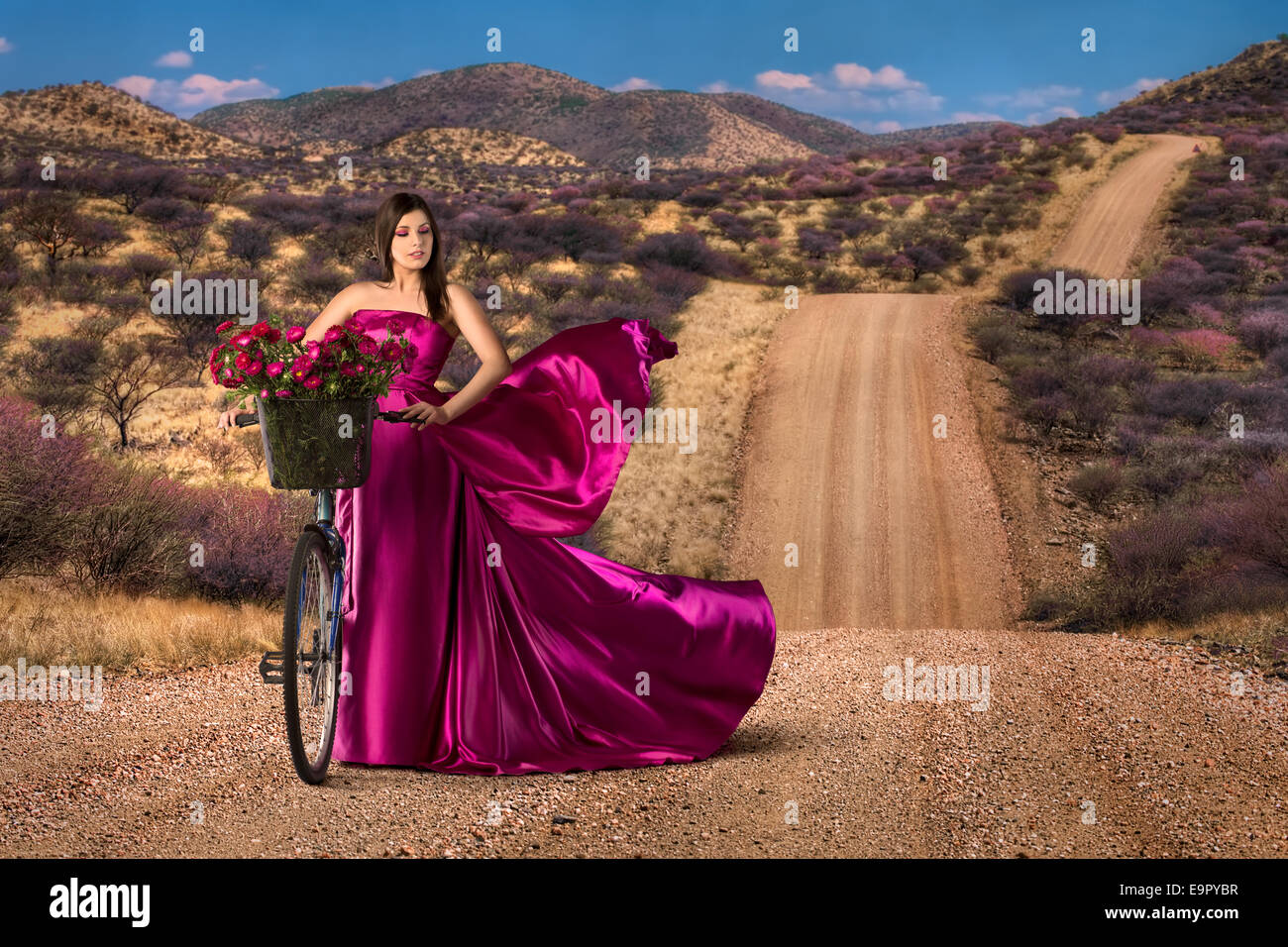 Femme avec vélo dans une belle robe rose Banque D'Images