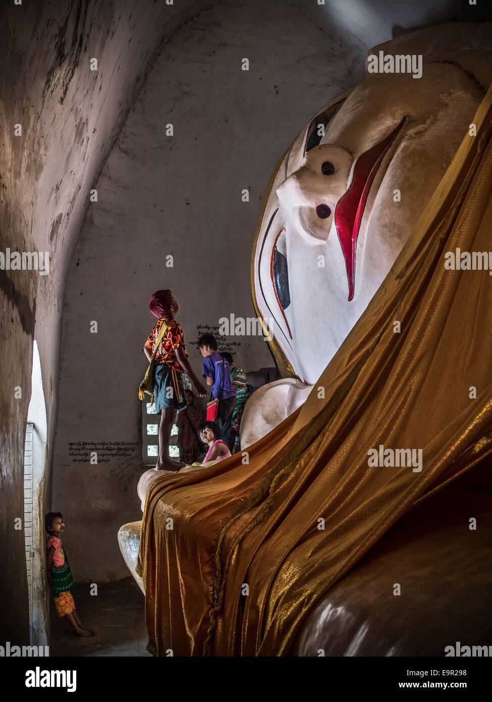 Les enfants birmans l'examen de l'ancienne statue de Bouddha couché temple Manuha à Bagan, Myanmar (Birmanie). Banque D'Images
